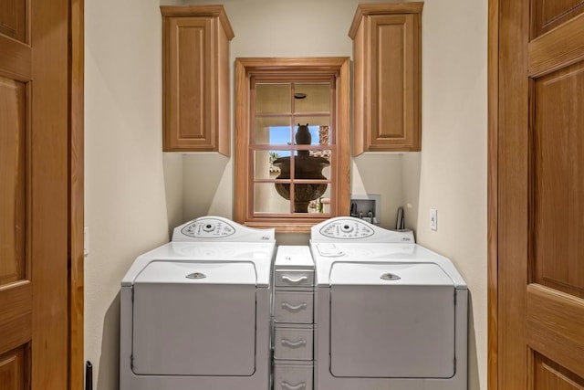 laundry room with washing machine and clothes dryer and cabinets