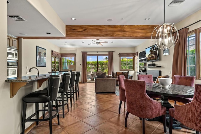 tiled dining area with ceiling fan with notable chandelier, beam ceiling, and sink