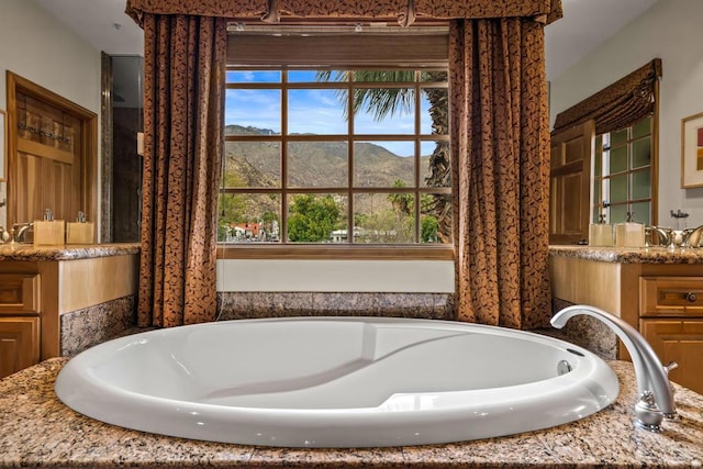 bathroom with a mountain view, vanity, and a bath