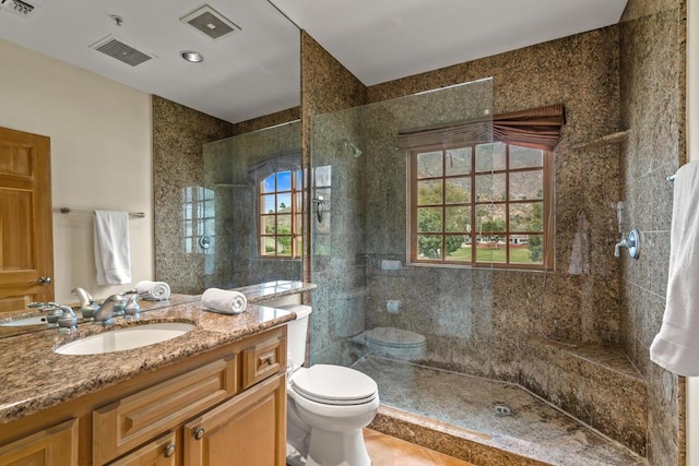 bathroom featuring vanity, toilet, and a tile shower