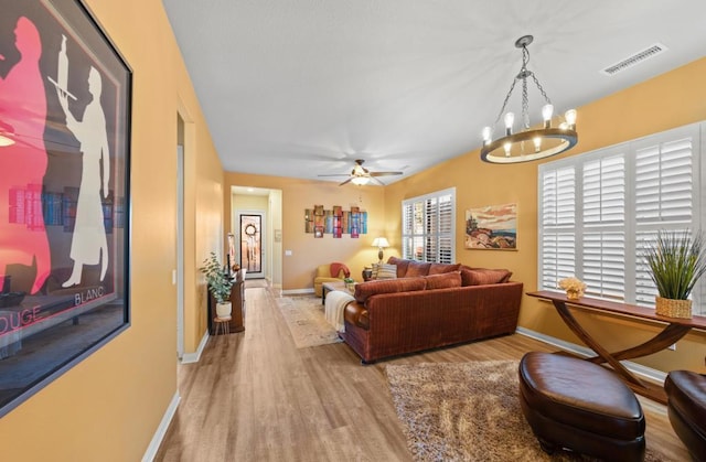 living room featuring ceiling fan with notable chandelier and light hardwood / wood-style floors