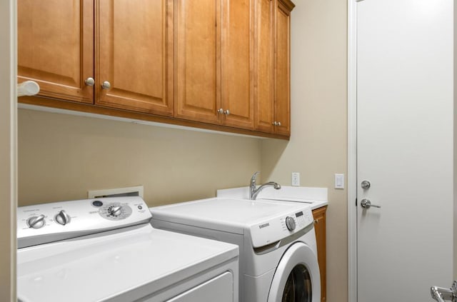 clothes washing area featuring washing machine and dryer and cabinets