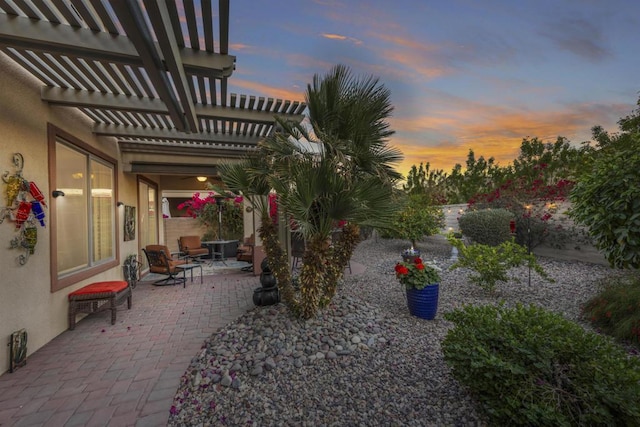 yard at dusk featuring a pergola and a patio area