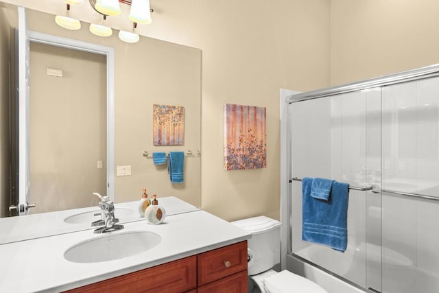 full bathroom featuring vanity, combined bath / shower with glass door, and toilet