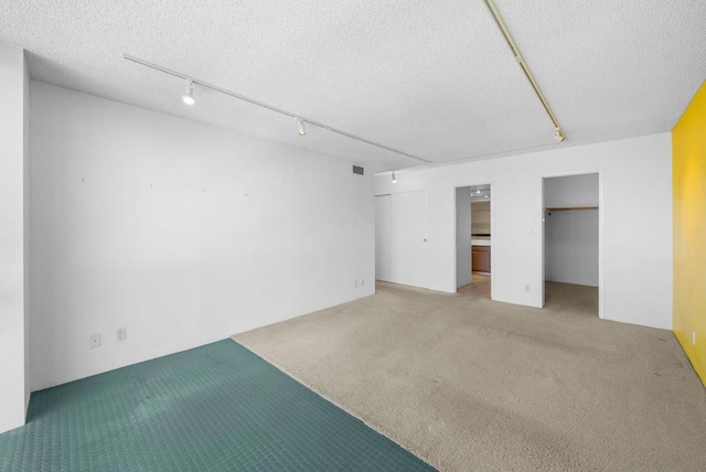 interior space featuring carpet flooring, a textured ceiling, and rail lighting