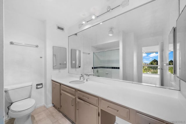 bathroom with walk in shower, tile patterned floors, vanity, and toilet