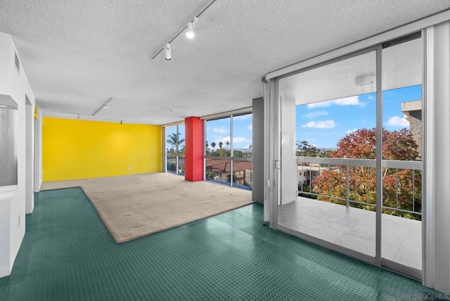 interior space featuring floor to ceiling windows, rail lighting, and a textured ceiling