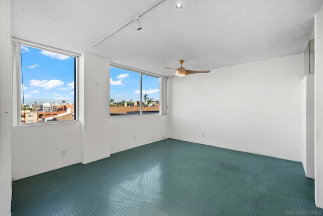 spare room featuring ceiling fan, track lighting, and a textured ceiling