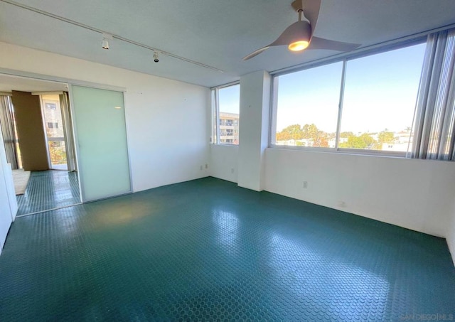 empty room with ceiling fan and track lighting