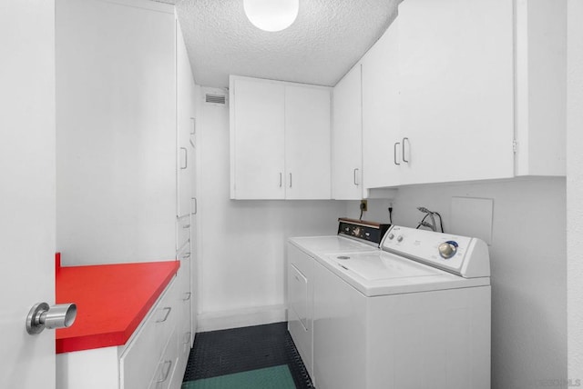 washroom featuring cabinets, washer and dryer, and a textured ceiling