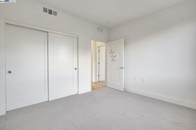 unfurnished bedroom featuring light colored carpet and a closet