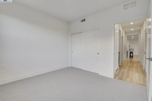 unfurnished bedroom featuring light colored carpet and a closet