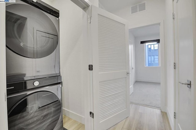 laundry room featuring light hardwood / wood-style flooring and stacked washer and clothes dryer