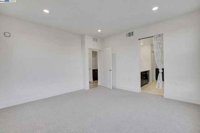 unfurnished bedroom featuring light carpet and connected bathroom