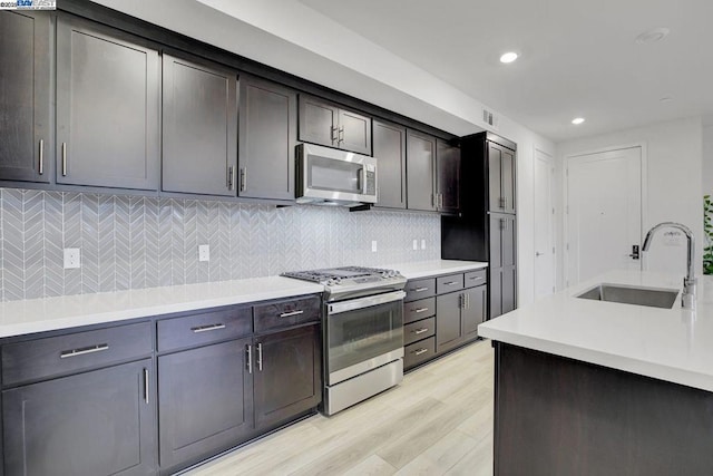 kitchen with sink, stainless steel appliances, light hardwood / wood-style floors, decorative backsplash, and dark brown cabinets