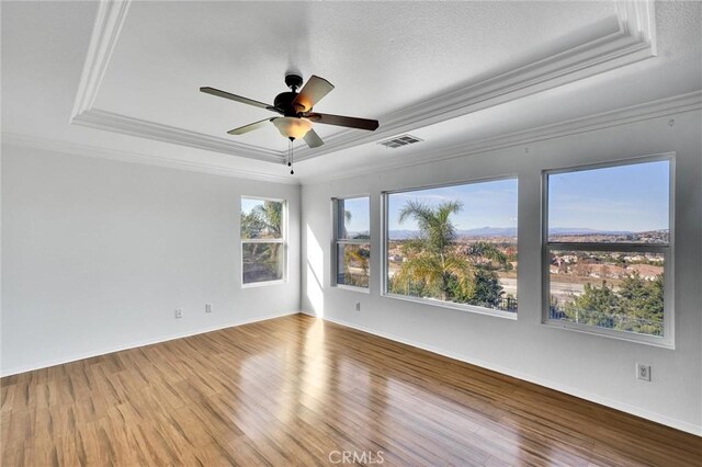 spare room with hardwood / wood-style flooring, ceiling fan, crown molding, and a tray ceiling