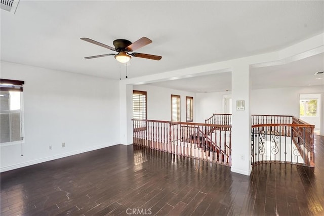 empty room with visible vents, dark wood finished floors, baseboards, and ceiling fan