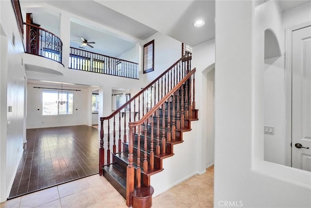 stairway with recessed lighting, a high ceiling, visible vents, baseboards, and tile patterned floors