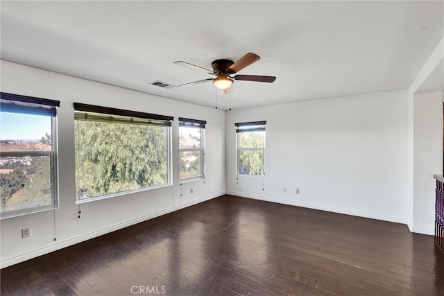 empty room featuring dark wood-style floors, baseboards, visible vents, and a ceiling fan