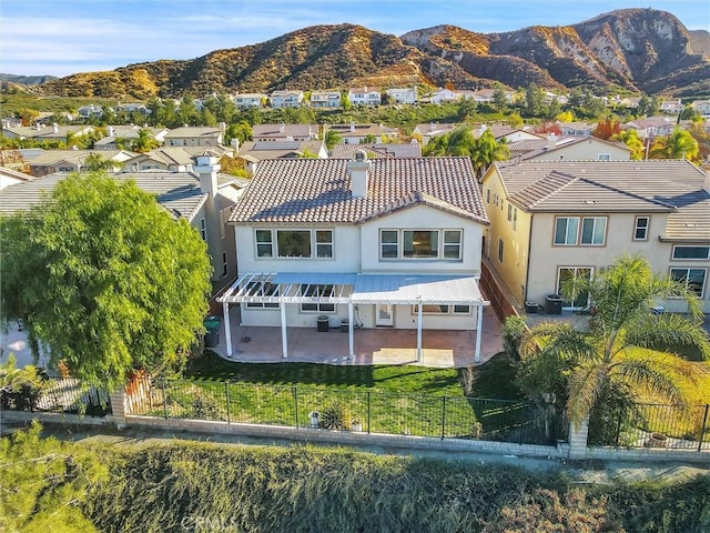 back of house with a fenced front yard, a residential view, and a mountain view