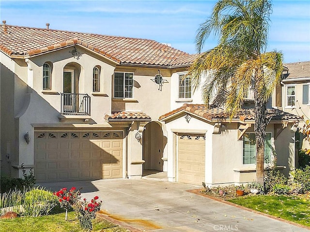 mediterranean / spanish home featuring a garage, stucco siding, driveway, and a tiled roof