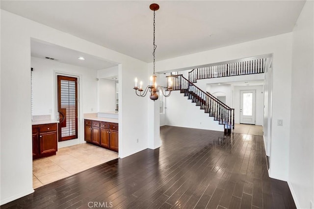 unfurnished dining area with light wood finished floors, stairs, visible vents, and a notable chandelier