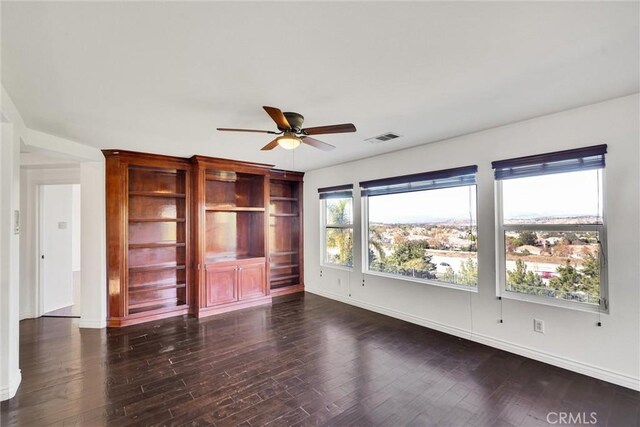 spare room featuring dark wood-style floors, visible vents, ceiling fan, and baseboards