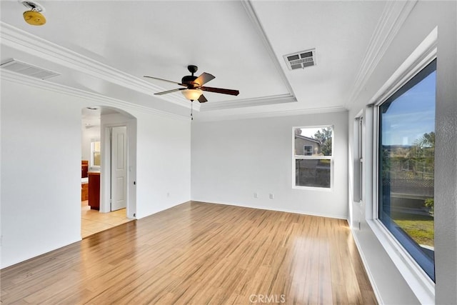 empty room featuring ornamental molding, light hardwood / wood-style flooring, ceiling fan, and a raised ceiling