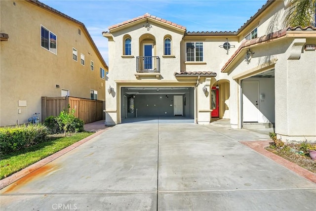 mediterranean / spanish-style home featuring driveway, a garage, a tiled roof, fence, and stucco siding