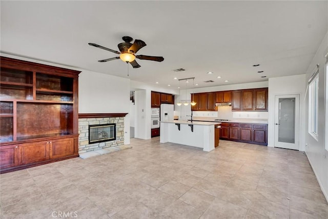 kitchen with a kitchen island with sink, a kitchen breakfast bar, open floor plan, light countertops, and hanging light fixtures