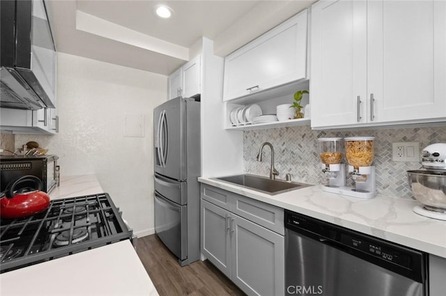 kitchen with dark wood-type flooring, sink, light stone counters, stainless steel appliances, and white cabinets