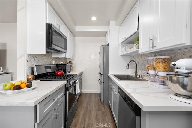 kitchen featuring sink, dark hardwood / wood-style flooring, stainless steel appliances, light stone countertops, and white cabinets