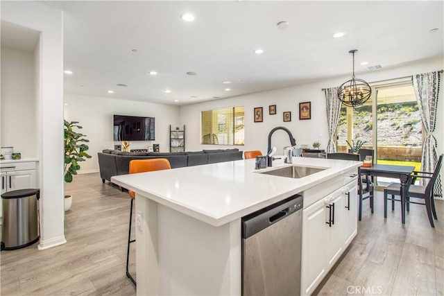 kitchen with dishwasher, a kitchen island with sink, sink, light hardwood / wood-style floors, and white cabinetry