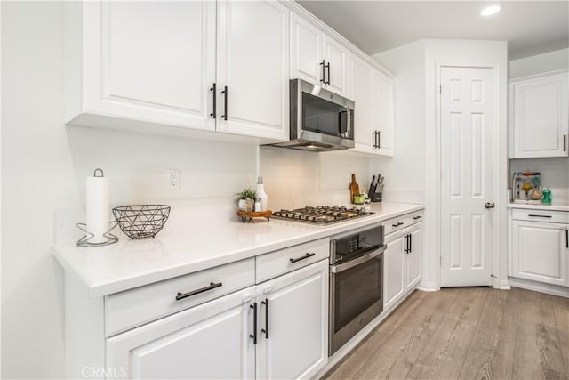 kitchen with appliances with stainless steel finishes, light wood-type flooring, and white cabinetry