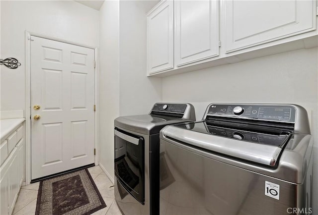 laundry area featuring washing machine and dryer, light tile patterned floors, and cabinets