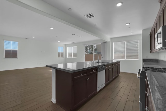 kitchen with stainless steel appliances, a kitchen island with sink, sink, beamed ceiling, and dark hardwood / wood-style floors