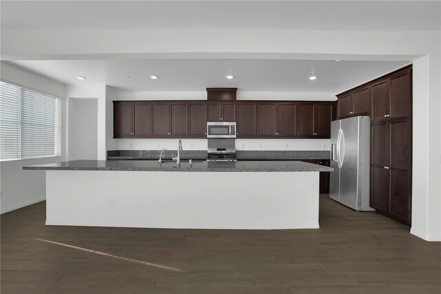 kitchen with dark brown cabinetry, sink, an island with sink, and appliances with stainless steel finishes