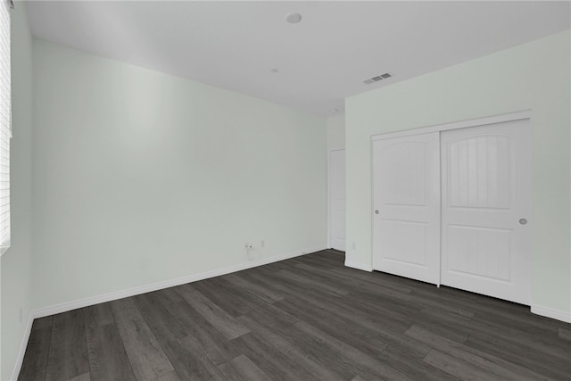 unfurnished bedroom with dark hardwood / wood-style flooring and a closet