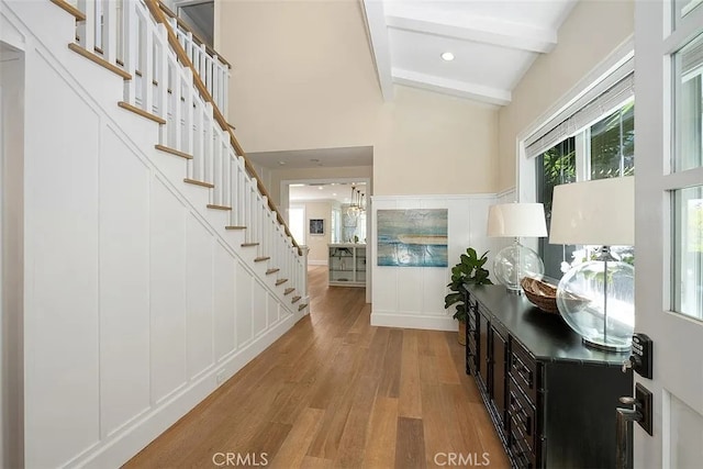 entryway with beamed ceiling and light wood-type flooring