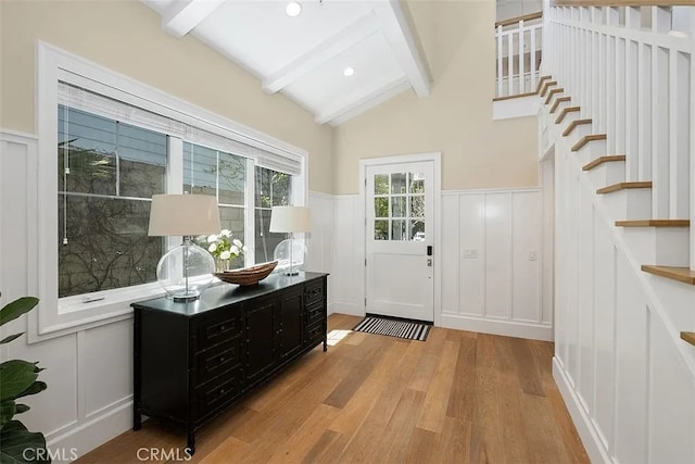 doorway to outside featuring lofted ceiling with beams and light wood-type flooring