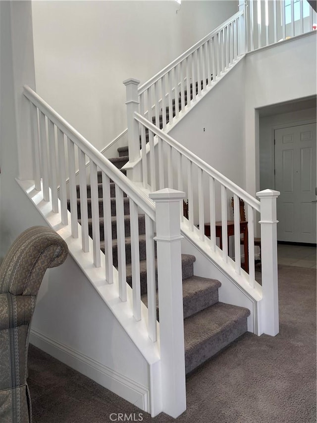 staircase with carpet and a towering ceiling