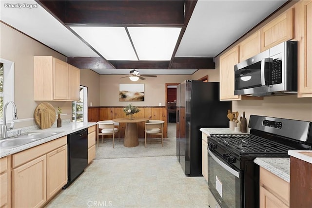 kitchen featuring sink, light brown cabinets, wood walls, and appliances with stainless steel finishes