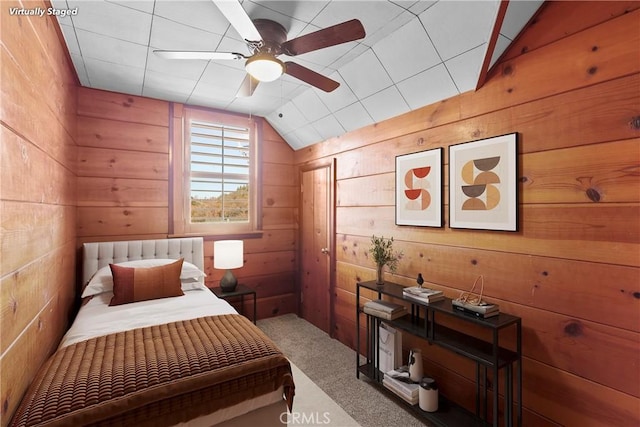 bedroom featuring ceiling fan, lofted ceiling, and wooden walls