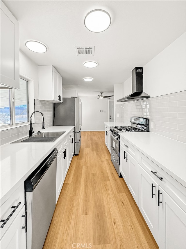 kitchen featuring white cabinets, sink, wall chimney range hood, and stainless steel appliances