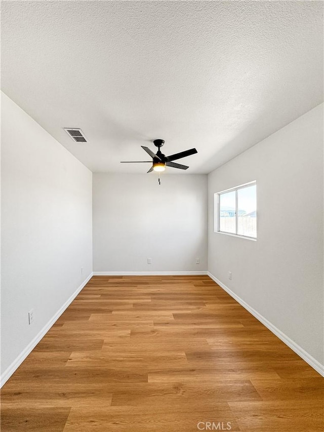 empty room with ceiling fan, light hardwood / wood-style floors, and a textured ceiling