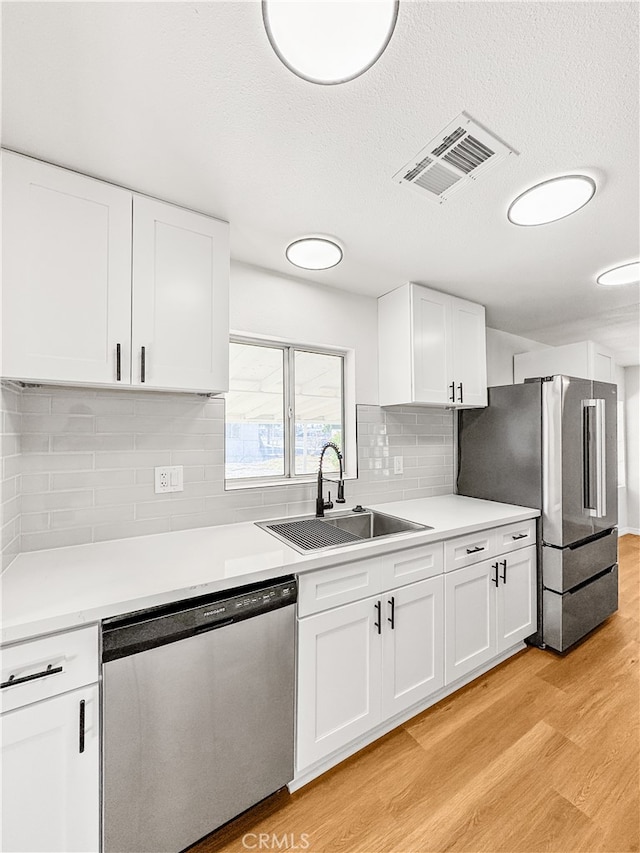 kitchen featuring sink, white cabinetry, stainless steel appliances, and light hardwood / wood-style flooring