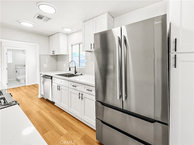 kitchen featuring white cabinetry, sink, appliances with stainless steel finishes, and light hardwood / wood-style flooring