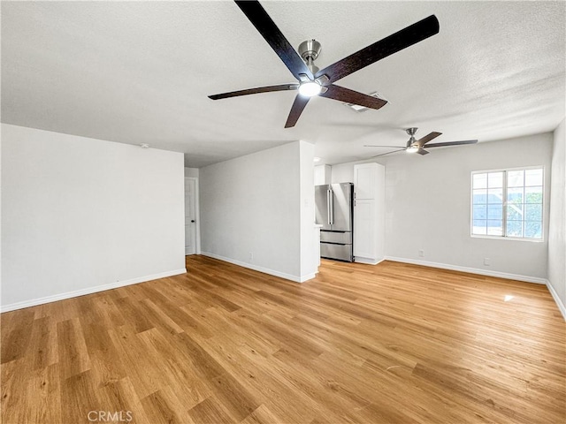 unfurnished living room featuring ceiling fan, a textured ceiling, and light wood-type flooring