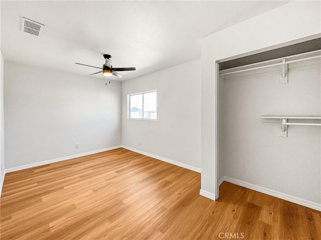 unfurnished bedroom featuring ceiling fan, a closet, and wood-type flooring