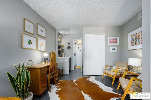 sitting room featuring dark tile patterned floors and a textured ceiling